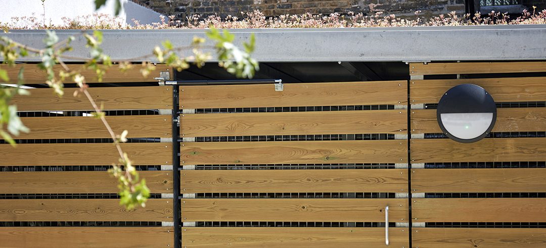 Timber clad metal gate with gas strut closer, lights and branch in foreground