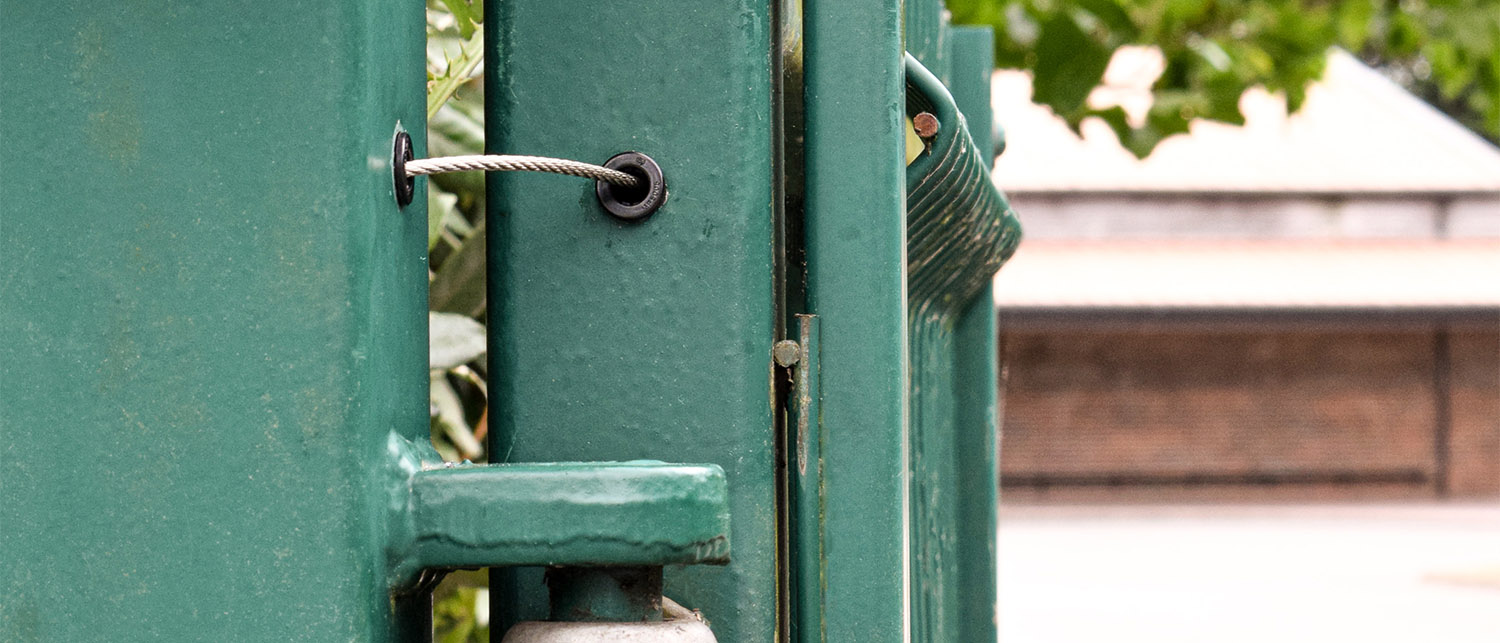 Gate tether installed on green metal gate with hook and eye hinges