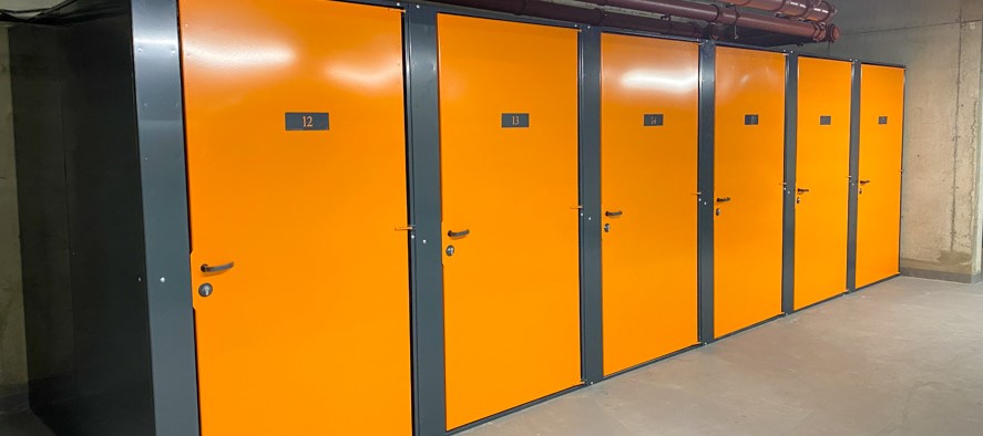 Set of six storage units with yellow doors and grey frames. Units are numbered starting with 12 to 17 from left to right.