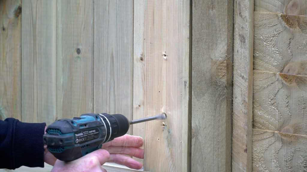 Person using drill to drill hole in timber gate