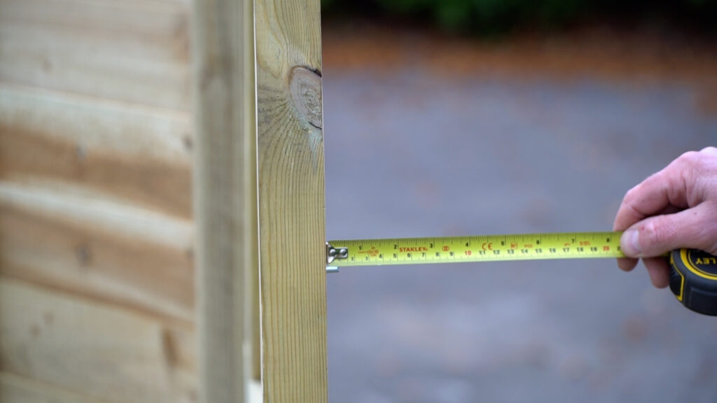 Person measuring the length of screws using yellow measuring tape