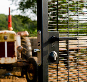 bolt-on gate lock with key access on gate. Gate stands in front of a tractor.