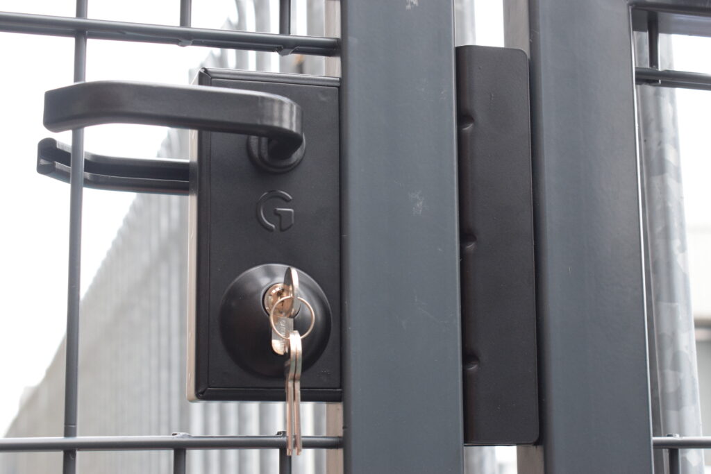 Serrure de portail avec accès par clé sur un portail métallique à grillage gris