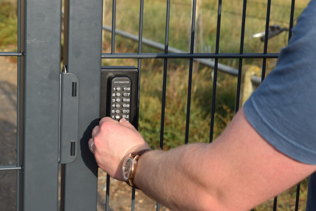 man opening combination keypad lock with code on metal gate