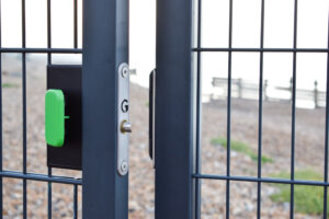 digital gate lock with green push pad on gravel