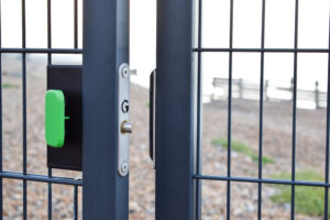 serrure de portail numérique avec bouton poussoir vert sur le gravier