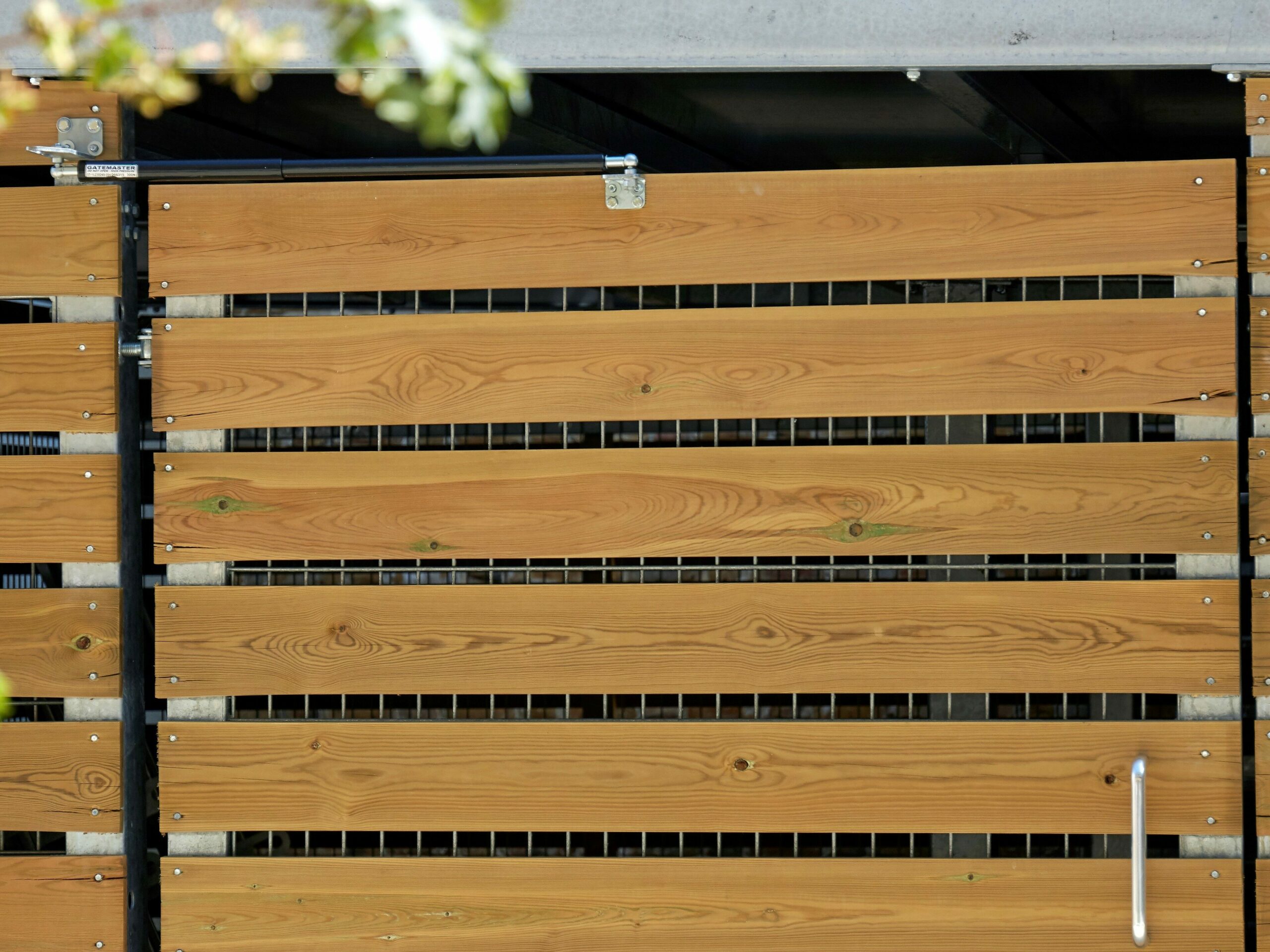 Wooden gate with gas strut closer on top of bike storage entrance