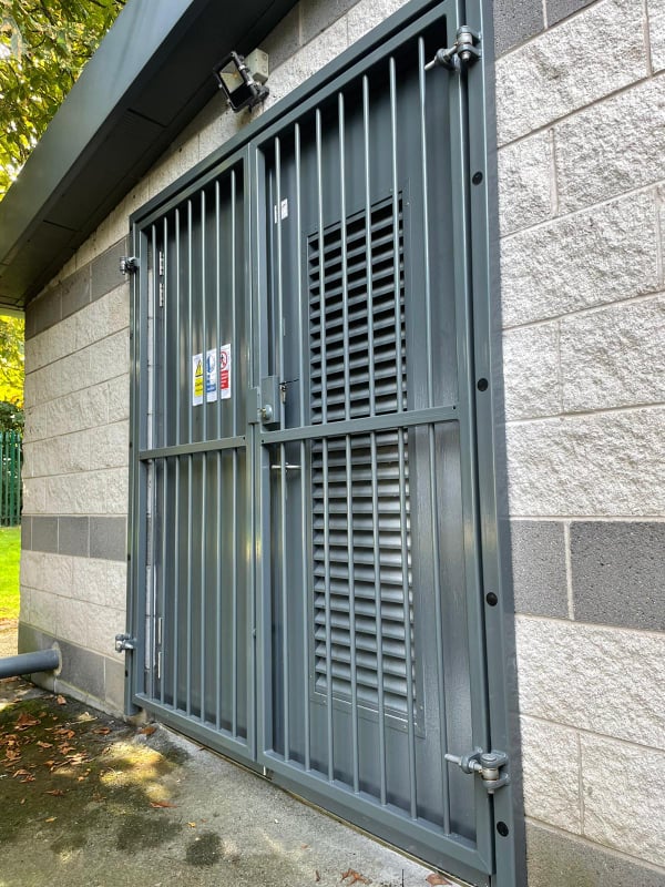 grey metal gate in front of access door with heavy duty industrial hinges