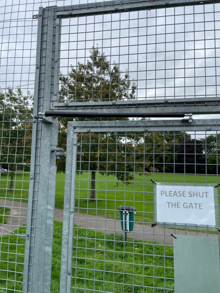 Tennis club entrance gates with controlled gate closer installed on top of mesh fencing and gate