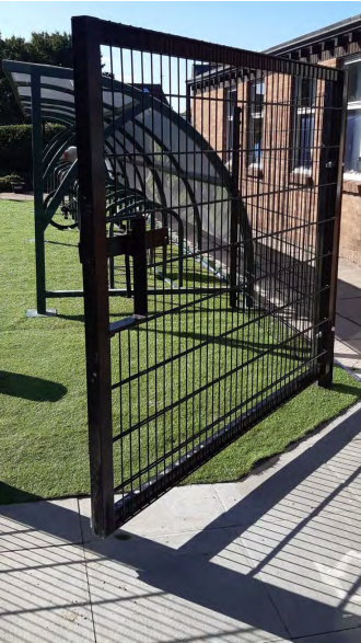 Black mesh gate in front of bike storage racks on school grounds