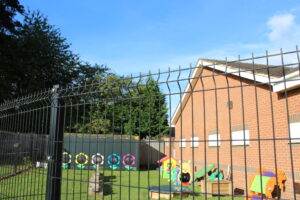 Mesh fencing in front of a nursery with toys in the front garden.