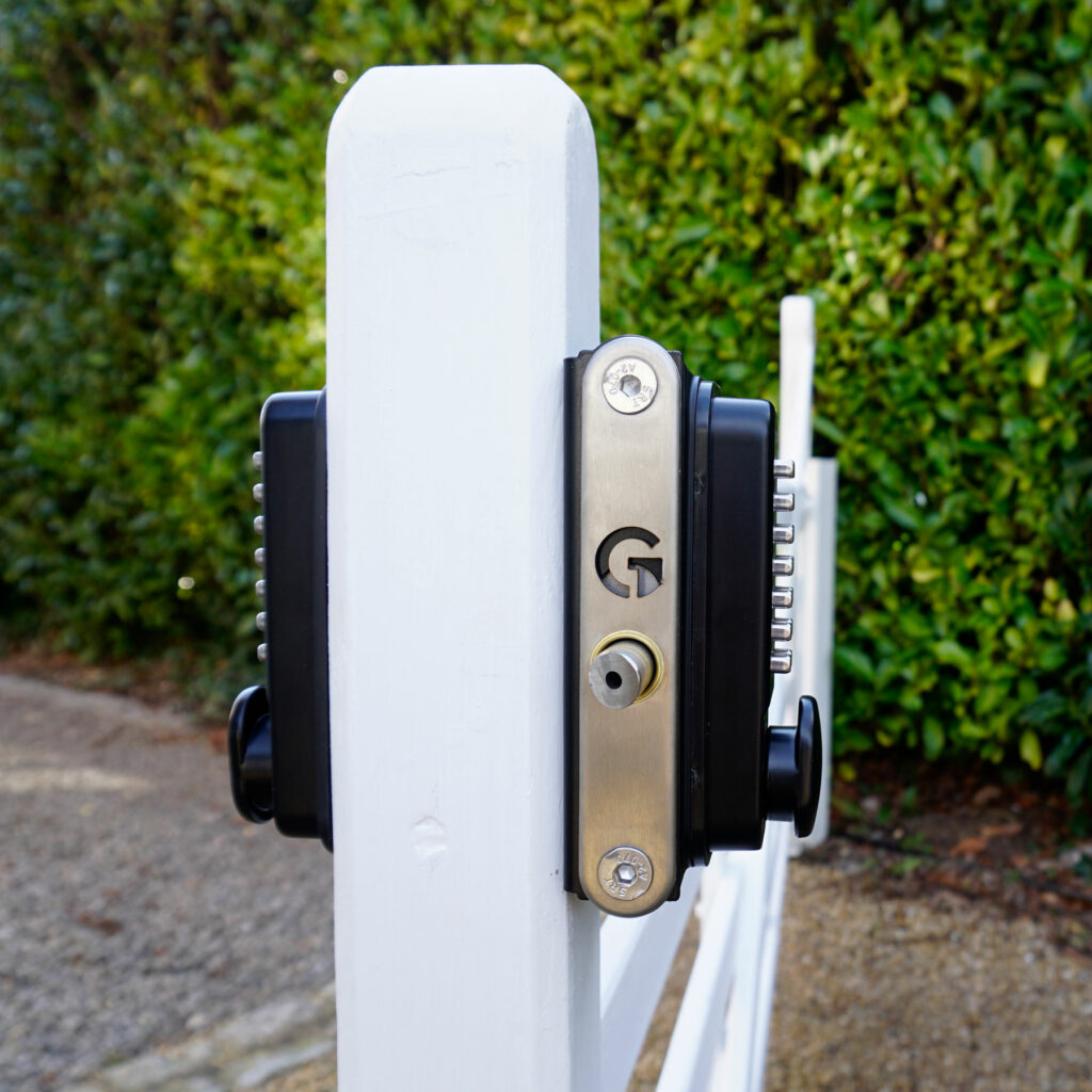 gate lock on a white wood gate showing front and back code keypads